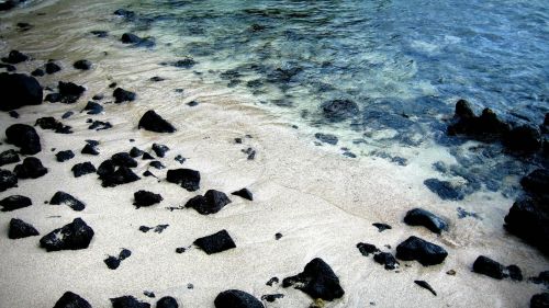 Black rocks on white sand beach HD Wallpaper