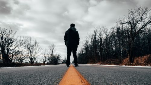 Lonely man standing at the middle of a road HD Wallpaper