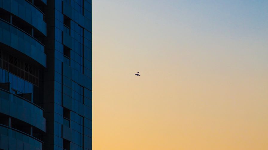 Plane flying next to skyscapers HD Wallpaper