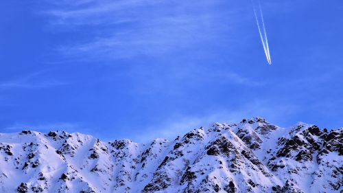 Plane flying over snowy mountains HD Wallpaper